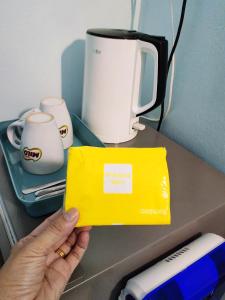 a person holding up a yellow box on a counter at Kapar Homestay@Master Room/Private Bathroom/Private Car Park/1-2pax in Kapar