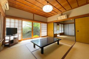 高野山 宿坊 宝城院 -Koyasan Shukubo Hojoin- في كوياسان: غرفة معيشة مع طاولة وتلفزيون