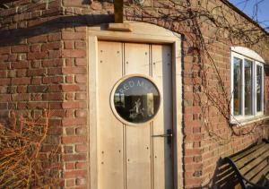 una puerta de madera con un espejo redondo en un edificio de ladrillo en Red Mill, en Haddiscoe