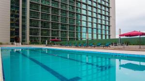 una piscina con sillas y sombrillas frente a un edificio en The Floorspace Imperial Suites Apartment, en Kuching
