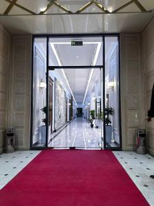 un grand couloir avec moquette rouge et portes en verre dans l'établissement Royal Plaza, à Karshi