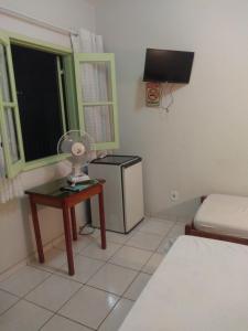 a small room with a bed and a table with a fan at Pousada Samambaia SL in São Lourenço