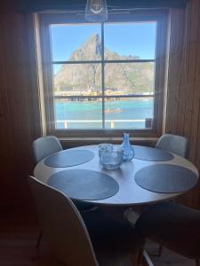 a table with chairs in front of a large window at Rostad Retro Rorbuer in Reine