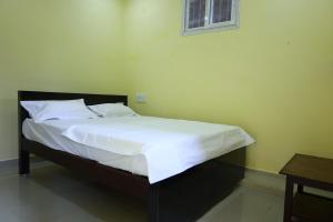 a bedroom with a bed with white sheets and a window at MSN Residency in Srikalahasti