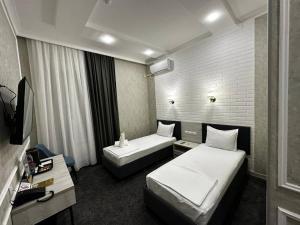Cette chambre comprend deux lits et une télévision. dans l'établissement Royal Plaza, à Karshi