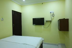 a room with a bed and a tv on the wall at MSN Residency in Srikalahasti