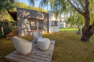 una casa con dos sillas blancas y un árbol en Mar & Campo en Santa Teresita