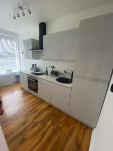 a kitchen with white cabinets and a wooden floor at Luxevibe apartment in Blackpool