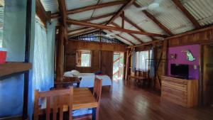 ein Zimmer mit einem Bett, einem Tisch und einem Fernseher in der Unterkunft Casa Pitahaya Marbella with AC, Swimming Pool, Skate Bowl & walking distance Beach for Surfers and Nature Lovers in Marbella