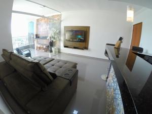 a living room with a couch and a tv at TH Flats GV Shopping in Governador Valadares