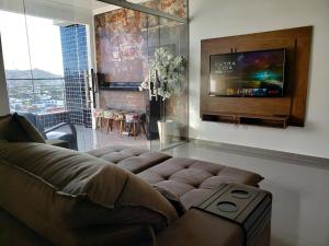 uma sala de estar com um sofá e uma televisão de ecrã plano em TH Flats GV Shopping 403 em Governador Valadares