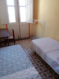 1 Schlafzimmer mit 2 Betten, einem Tisch und Fenstern in der Unterkunft Casa Escuela in Valle Gran Rey