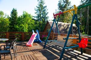 un parque infantil con banco y equipo de juegos en una terraza en Biały Domek, en Międzybrodzie Bialskie