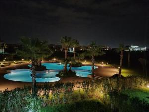 a group of pools with palm trees at night at Appartement Prestigia Golf City Marrakech - Porte Agate - Gated community Rez-de-Jardin in Marrakesh