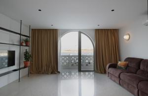 a living room with a couch and a large window at VILLA JOSEPH in St Paul's Bay