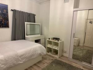 倫敦的住宿－Spacious and homely one bedroom，一间卧室配有一张床和一张桌子上的电视