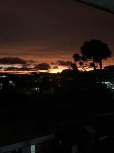 een zonsondergang boven een stad met een boom op de voorgrond bij Apartamento em ótima localização in Canela