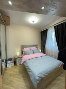 a bedroom with a large bed with pink and blue pillows at Apartman sa ljuljaskom in Zlatibor