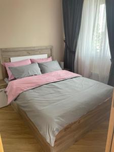 a bed with pink and white sheets and a window at Apartman sa ljuljaskom in Zlatibor +42 photos