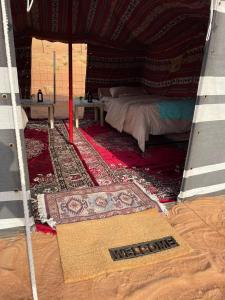 um quarto com uma cama e um tapete numa tenda em Authentic Desert Camp - Al Wasil 