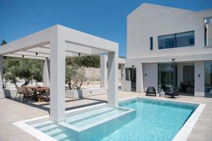 a villa with a swimming pool in front of a house at Sunny Vacay Villa in Stérnai