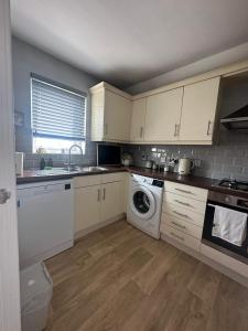 een keuken met witte kasten en een wasmachine bij Brownsea Island View Penthouse in Poole