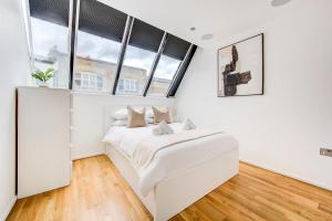 a white bedroom with a bed and windows at Shoreditch 3-Storey Maisonette - by Living Elite Apartments in Shoreditch