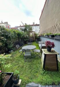 un patio con mesa y sillas en el césped en Jasmin étoilé duplex avec jardin 15 min de Paris, en Alfortville