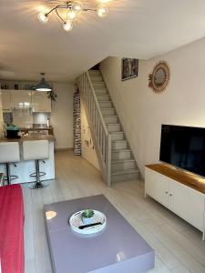 - un salon avec un escalier, une table et une télévision dans l'établissement Jasmin étoilé duplex avec jardin 15 min de Paris, à Alfortville