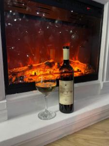 a bottle of wine and a glass in front of a fireplace at Apartman sa ljuljaskom in Zlatibor