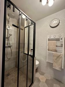 La salle de bains est pourvue d'une douche et d'une horloge murale. dans l'établissement Jasmin étoilé duplex avec jardin 15 min de Paris, à Alfortville