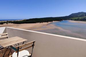 a wooden table and chairs on a balcony overlooking a beach at IAROS Pueblo del Sol in Mogro
