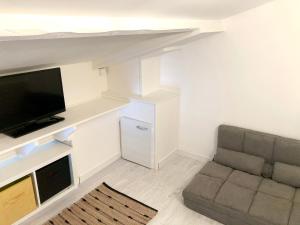 ein Wohnzimmer mit einem Sofa und einem Flachbild-TV in der Unterkunft Studio bord de mer in Ouistreham