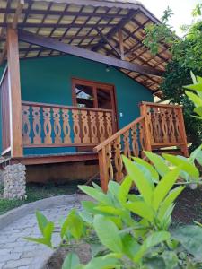 une maison avec une terrasse en bois et une porte dans l'établissement Pousada Vale da Cachoeira, à Visconde de Mauá