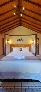 - une chambre avec un grand lit blanc et des plafonds en bois dans l'établissement Pousada Vale da Cachoeira, à Visconde de Mauá