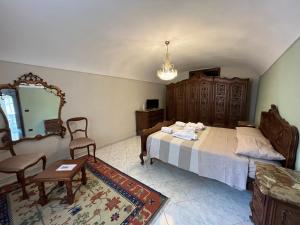 ein Schlafzimmer mit einem Bett, einem Spiegel und einem Stuhl in der Unterkunft Casa dell’Annunziata in Chiusa di Pesio