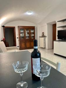 una botella de vino y dos copas de vino en una mesa en Casa dell’Annunziata en Chiusa di Pesio