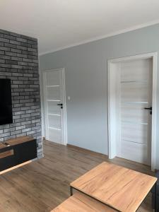 a living room with a tv and a brick wall at APARTAMENT DĘBOWY in Trzcianka