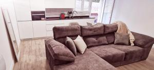 a brown couch in a living room with a kitchen at Piso de lujo 2 habitaciones in Las Rozas de Madrid
