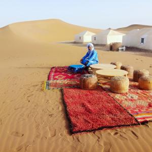 a woman sitting in the sand in the desert at Sahara wild camping in Mhamid