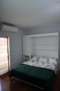 a bedroom with a bed with a green blanket on it at Prima Apartments in Pogradec