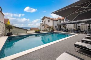 a swimming pool in a house with chairs and an umbrella at Crikvenica Apartment 9 in Crikvenica