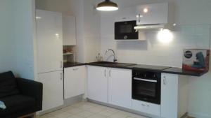 uma cozinha com armários brancos e um forno de fogão preto em Flat near Paris em Gennevilliers