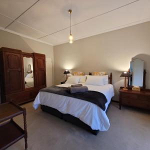 1 dormitorio con 1 cama grande y espejo en AppleBee Guest Cottages en Grahamstown