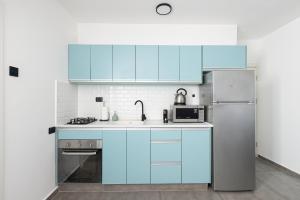 a kitchen with blue cabinets and a refrigerator at Nirvana 1BR Apt, Central Old Town, Private Balcony in Beer Sheva
