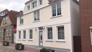 a white house on a street next to a brick building at FeWo Todeskino ``Altstadtflair`` in Heiligenhafen in Heiligenhafen