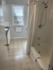 a white bathroom with a shower and a tub at Niagara Riverview Closest to Falls, Free Breakfast Delivered Daily in Niagara Falls