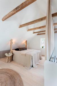 una camera bianca con un letto in una stanza con soffitti in legno di Hus 42 a Fårup