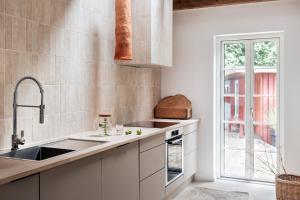 una cucina con armadi bianchi, lavandino e finestra di Hus 42 a Fårup