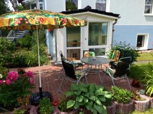 eine Terrasse mit einem Tisch, Stühlen und einem Sonnenschirm in der Unterkunft Kompass in Rostock